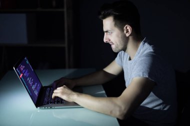 Program Geliştirme kavramı. Genç adam bilgisayar içinde belgili tanımlık karanlık ile çalışma