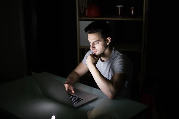 Vício noturno tardio na internet ou trabalhando até tarde homem usando laptop em uma mesa no escuro — Fotografia de Stock