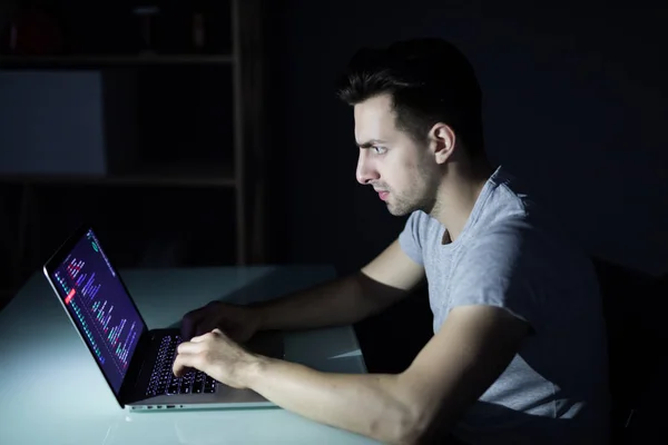 Single solitary computer hacker works in the dark committing crime in night