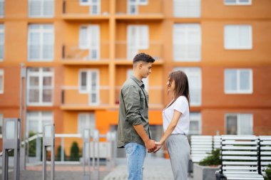 Çekici bir genç çift elele ve birbirine bakarak profil görünümü