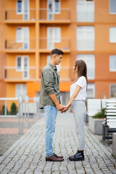 Vista del perfil de una atractiva pareja joven cogida de la mano y mirándose —  Fotos de Stock