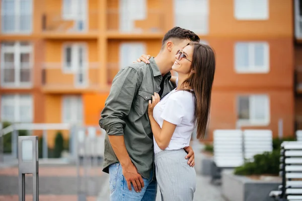 Jovem casal beijando na rua edifício no fundo — Fotografia de Stock