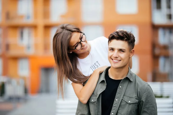 Hermosa pareja joven en gafas de sol mirándose y sonriendo mientras están al aire libre . —  Fotos de Stock