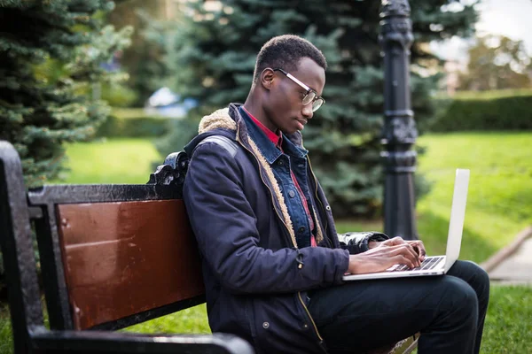 Joyful Africano americano homem usando computador ao ar livre no banco na rua — Fotografia de Stock