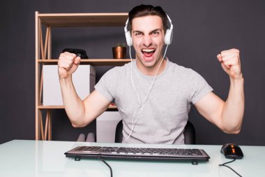 oynayan ve evde bilgisayar oyun kazanan bir kulaklık ile mutlu delikanlı