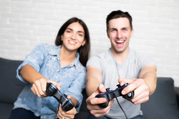 Νέοι χαριτωμένο ζευγάρι παίζοντας βιντεοπαιχνίδια βλέπουν κάμερα στο σαλόνι στο σπίτι — Φωτογραφία Αρχείου