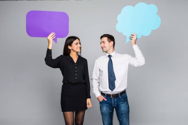 Rahat kıyafetler içinde güzel genç çift renkli konuşma balonları, kameraya bakarak ve gülümseyen tutuyor.