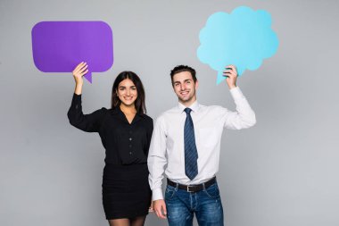 Güzel genç çift kameraya bakıyor ve gülümsüyor, gri üzerine konuşma balonları, tutuyor