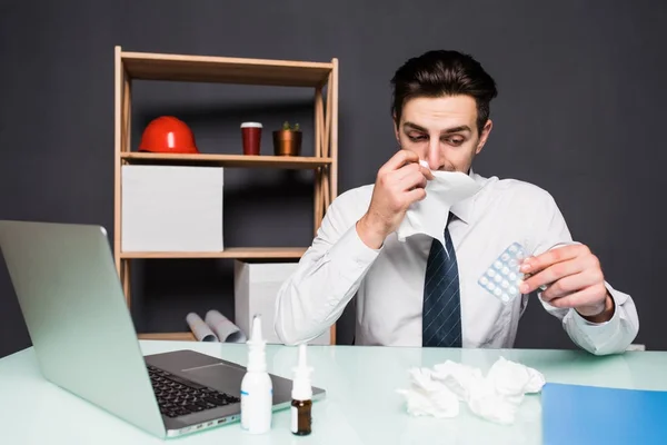 Um homem doente está sentado em seu local de trabalho no escritório se sentir doente e doente, tomar comprimidos remédio. Trabalho doente. Trabalho na estação fria . — Fotografia de Stock
