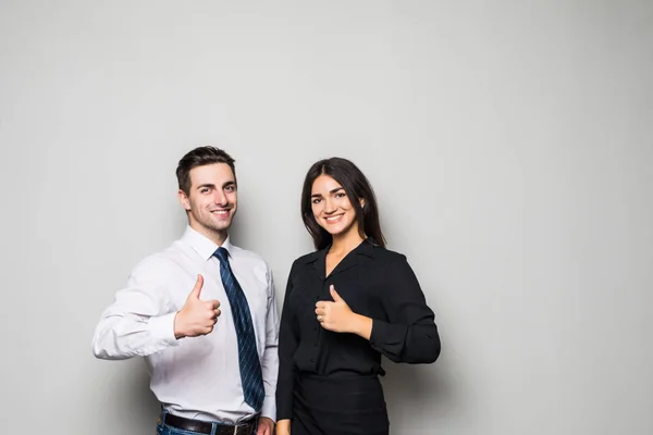 Two smiling happy businesspeople in formalwear showing thumbs-up on gray — Stock Photo, Image
