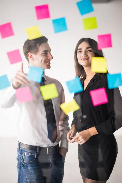 Start business planning en organisatie met jong koppel bij moderne kantoor interieur schrijven c HTING stickers maken. Kantoorwerk — Stockfoto