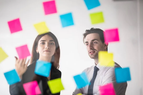 Business, opstarten, planning, beheer en mensen concept - gelukkig creatieve team schrijven op stickers bij office glas board in moderne kantoren — Stockfoto