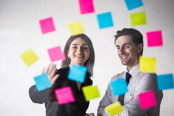 Business, opstarten, planning, beheer en mensen concept - gelukkig creatieve team schrijven op stickers bij office glas board in moderne kantoren — Stockfoto