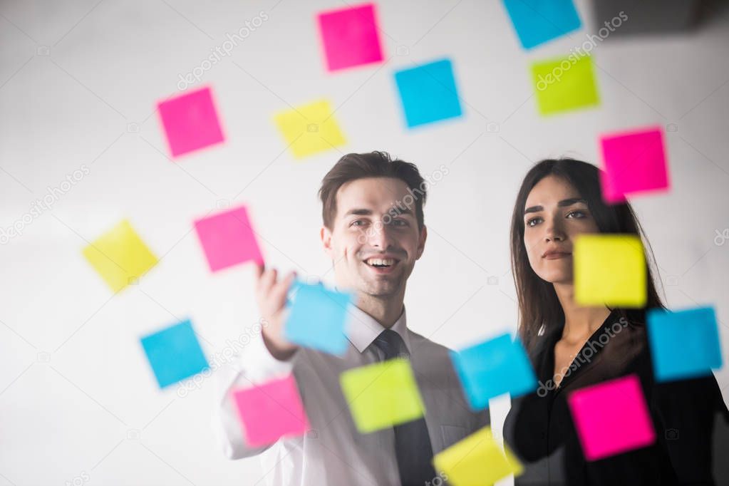start up business planning and making organization with young couple at modern office interior writing notes on stickers. Office work