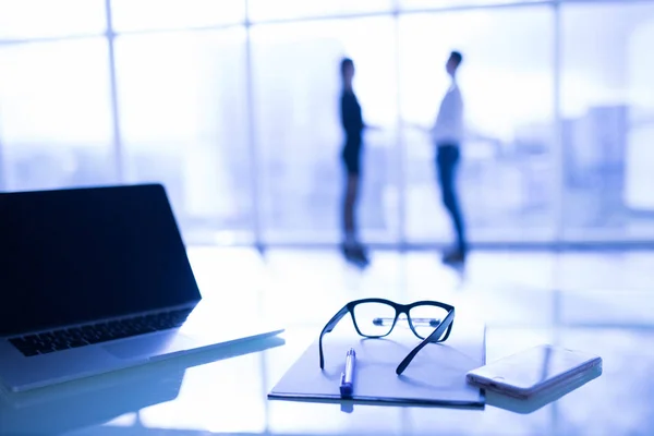 Close up van bril op Bureau met grafiek en laptop op zakelijke werkplek met zakelijke partners op achtergrond — Stockfoto