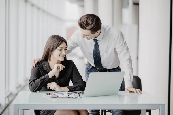 Empresario y mujer de negocios que trabaja con el ordenador portátil en la oficina moderna. Hombre discutir con la mujer planes . — Foto de Stock