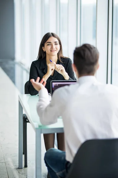 Business mensen man en vrouw hebben bijeenkomst in tabel In moderne kantoor tegen panoramische ramen. Focus op vrouw. — Stockfoto