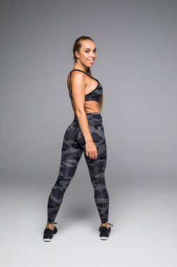 Dikiz atış spor içinde sağlıklı bir genç kadın. Kaslı kadın modeli ayakta uzak gri arka plan üzerinde boşaltmak bakmanın tam boy görüntü