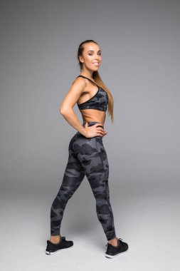 Dikiz atış spor içinde sağlıklı bir genç kadın. Kaslı kadın modeli ayakta uzak gri arka plan üzerinde boşaltmak bakmanın tam boy görüntü