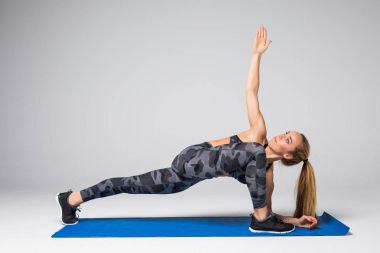 Güzel genç model çalışma dışarı, mat gri yoga egzersiz germe yapıyor. Spor aktif yaşam tarzı kavramı. Tam uzunlukta, yan görünüm