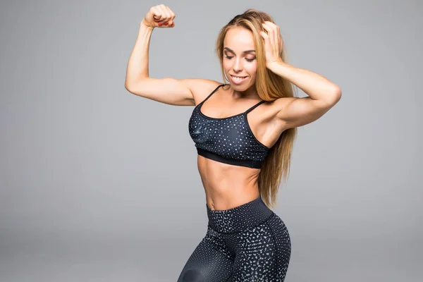 Nahaufnahme einer jungen Frau, die im Fitnessstudio posiert und Muskeln zeigt — Stockfoto