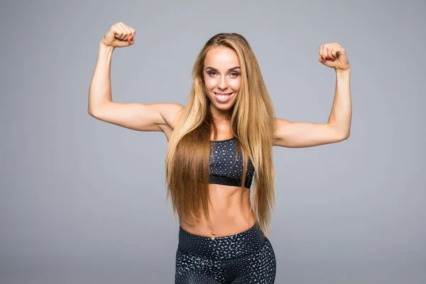 Mujer deportiva está mostrando sus manos fuertes sobre fondo gris — Foto de Stock