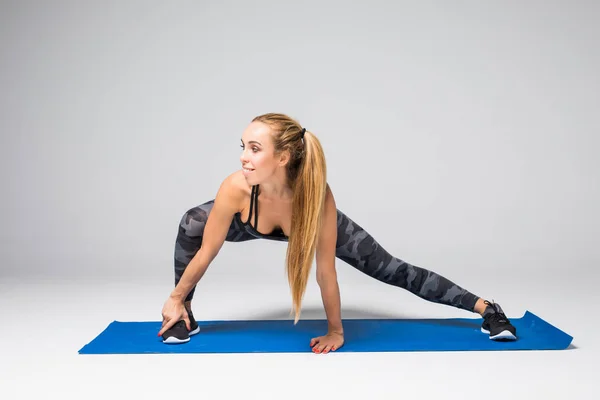 Side view porträtt av vacker ung kvinna som arbetar mot grå vägg, gör yoga eller pilates träning på grå — Stockfoto