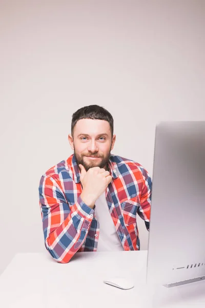 Красивый бородатый мужчина, работающий с белым компьютером за рабочим столом — стоковое фото