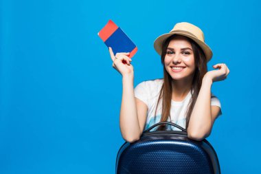 Çantalı güzel bir kadın mavi arka planda pasaportu tutuyor.
