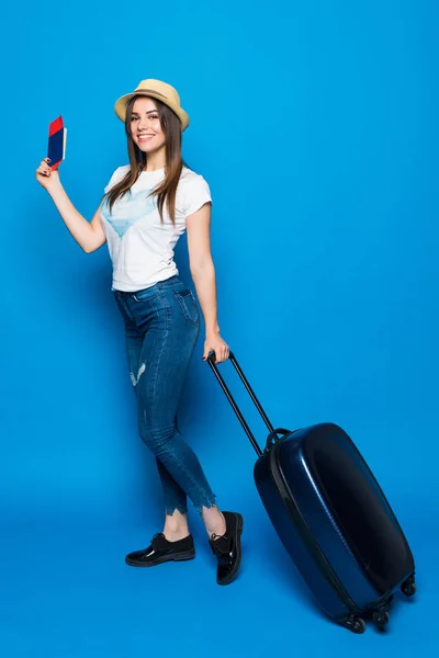 Joven mujer atractiva en vaqueros azules y un sombrero con una maleta aislada sobre fondo azul. Concepto de recreación y turismo . — Foto de Stock