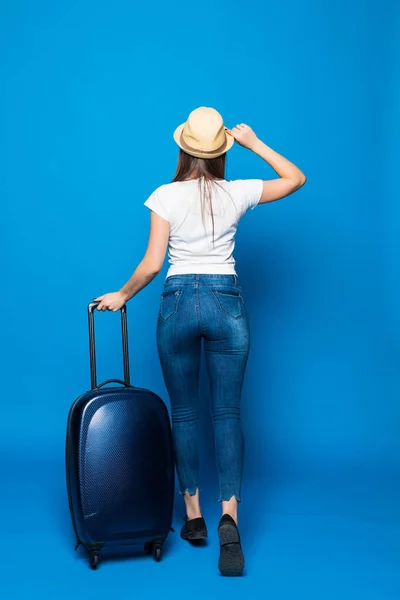 Vista trasera de la mujer que camina con la maleta. hermosa chica en movimiento. vista trasera del viajero con equipaje Aislado sobre fondo azul . — Foto de Stock