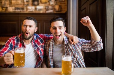 İki adam bira ile TV izlemek onların favori takım zafer pub sevinirler