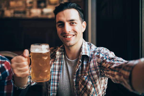 地元のパブでビールのリラックスのガラスと selfie を取って喜んで叫んで興奮して若い男のショット — ストック写真
