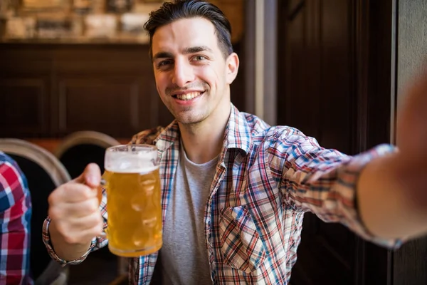 Conceito de pessoas e tecnologia - homem com smartphone bebendo cerveja e tomando selfie no bar ou pub — Fotografia de Stock