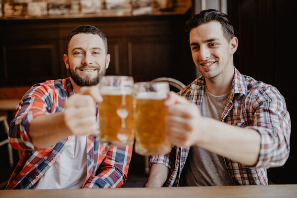 happy male friends drinking draft beer at bar or pub and clinking glasses