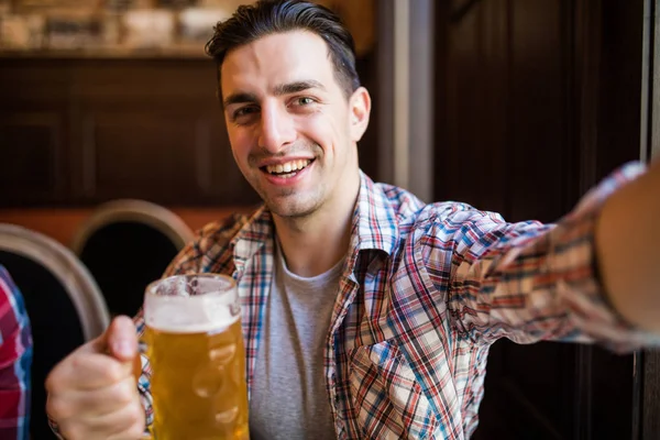Skott av en upphetsad ung man skrek glatt tar en selfie med ett glas öl avkopplande på den lokala puben — Stockfoto