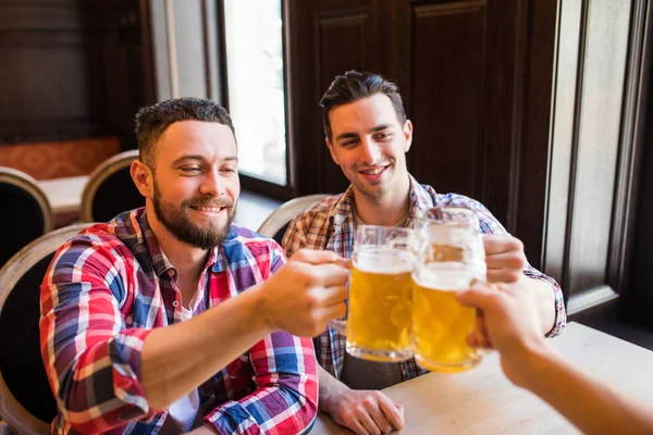 Gärna manliga vänner som dricker öl och spottar glasögon på bar eller pub — Stockfoto