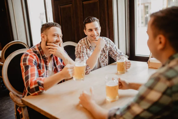 Glada vänner att ha kul och dricka öl i puben. — Stockfoto