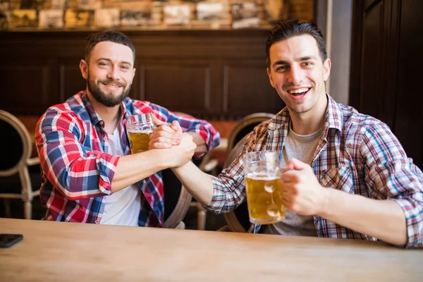 Feliz jovem barbudo homem rindo alto cinco seu amigo enquanto tomando cerveja no pub juntos — Fotografia de Stock