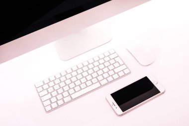 Beyaz arka plan üzerinde izole bir masa üzerine yalan klavye ve fare, cep telefonu, metalik dizüstü bilgisayar ile metalik pc ile modern ofis işyeri.