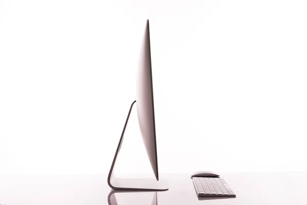 Клавиатура и экран компьютера на белом столе с отражением на белом фоне — стоковое фото