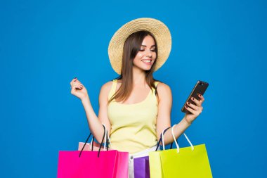 Mavi arka plan üzerinde bir alışveriş satış, cep telefonu kullanan mutlu kadın