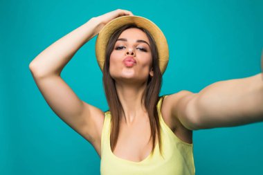 Smartphone cep telefonu ile bir renk arka plan üzerinde izole öpücük göndermek selfie fotoğraf yapma gülümseyen güzel kadın portresi