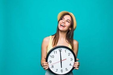 Saat 12 ile bir tutan genç mutlu kadın yeşil bir arka plan üzerinde saat. Beyaz arka plan üzerinde duvar saati ile pozitif genç ve güzel kadın portresi