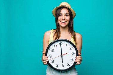 Saat 12 ile bir tutan genç mutlu kadın yeşil bir arka plan üzerinde saat. Beyaz arka plan üzerinde duvar saati ile pozitif genç ve güzel kadın portresi