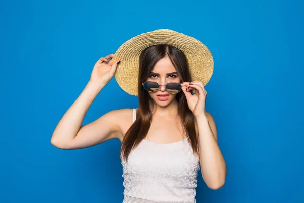 Beauté souriante jeune femme avec des lunettes de soleil et un chapeau dans un style moderne sur un fond de mur bleu . — Photo