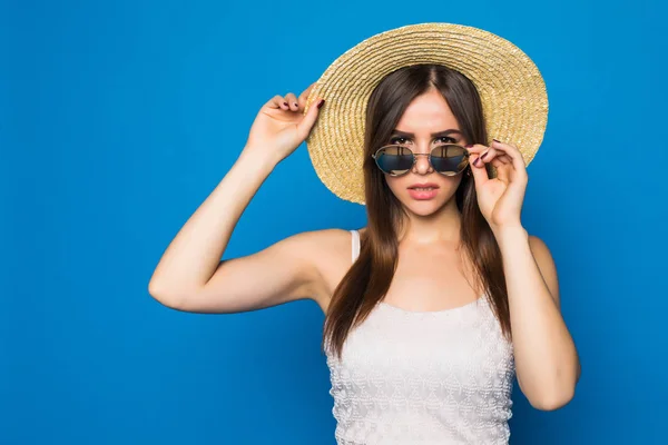 Beauté souriante jeune femme avec des lunettes de soleil et un chapeau dans un style moderne sur un fond de mur bleu . — Photo