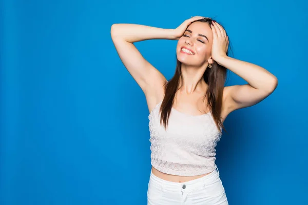 Portret lacht vrolijk gelukkig jonge vrouw met handen op het hoofd moe geïsoleerd blauwe achtergrond. — Stockfoto