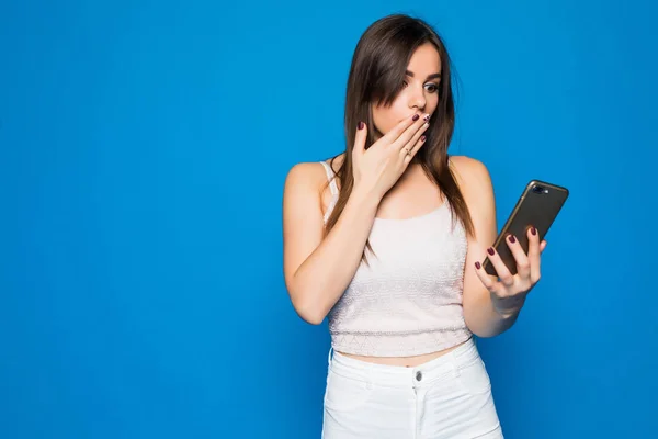 Young beauty woman typing in the phone on blue background — Stock Photo, Image