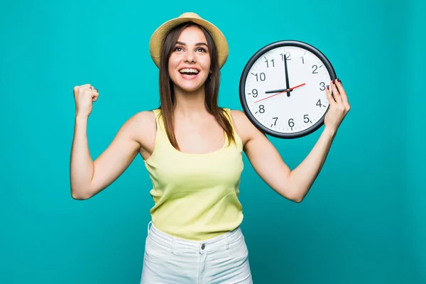 Giovane donna eccitata in possesso di un orologio che mostra quasi 9 con felici emozioni vittoria su sfondo verde — Foto Stock